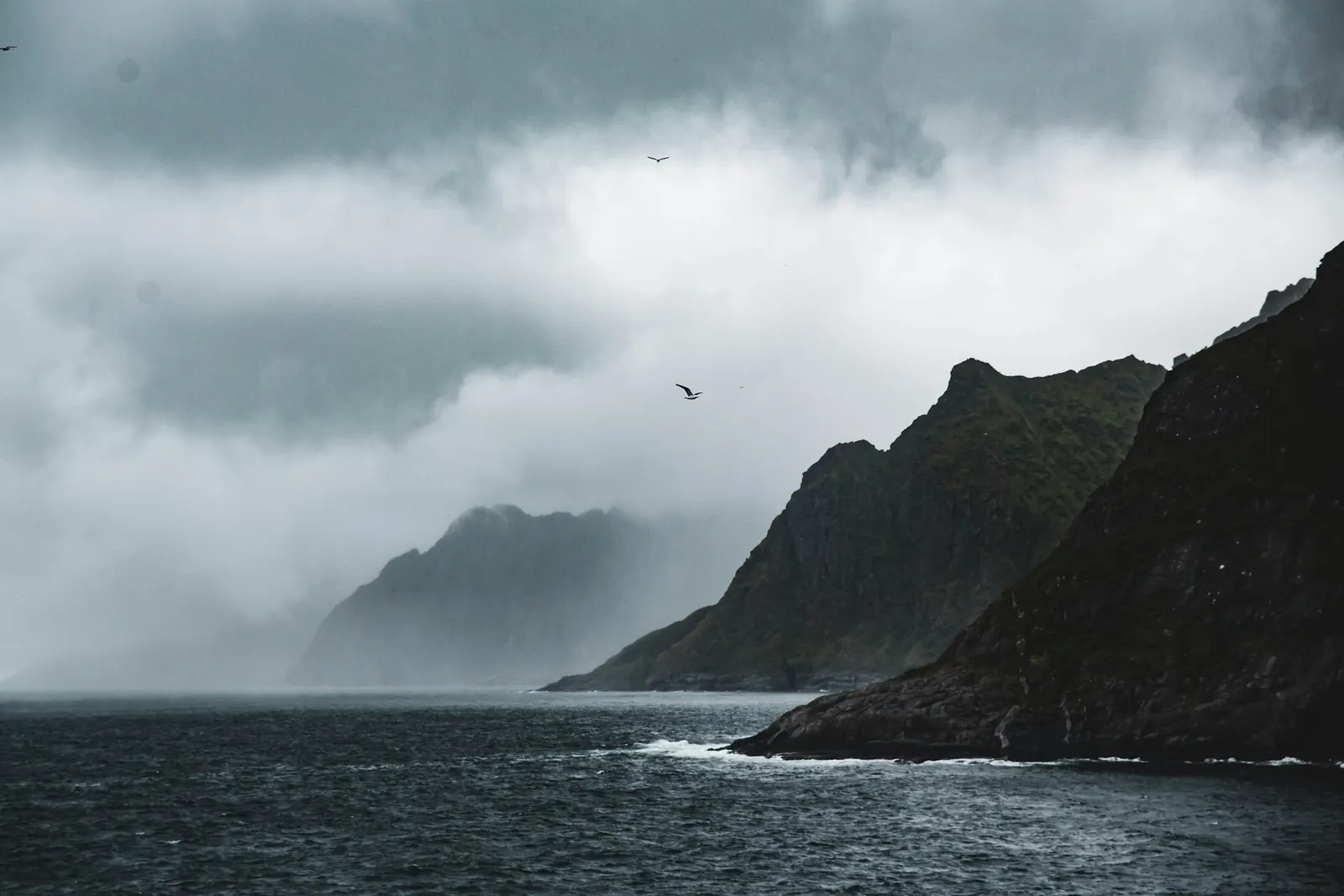 Stormy Norwegian coastline with mountains rising from the sea