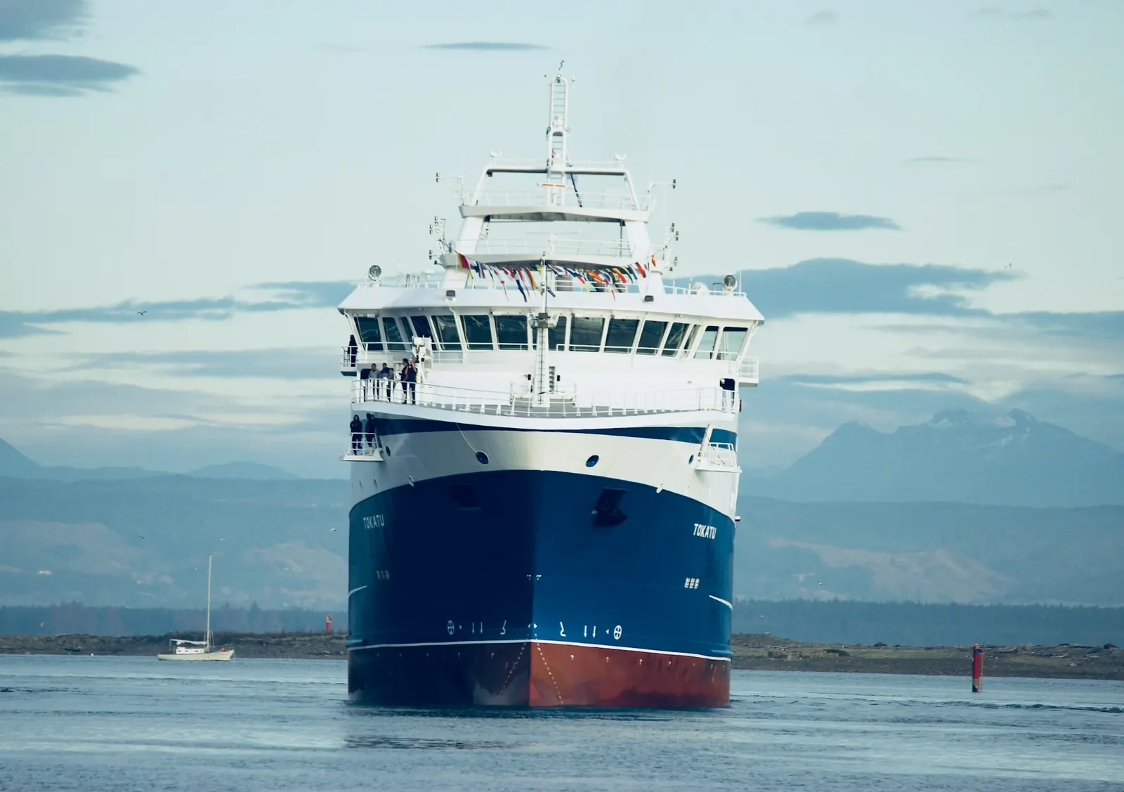 Vessel with a blue hull heading in towards the coast